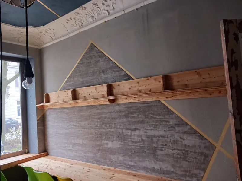 Erhaltener Deckenstuck im Altbau über einer neu gestalteten Wand mit goldenen Linien