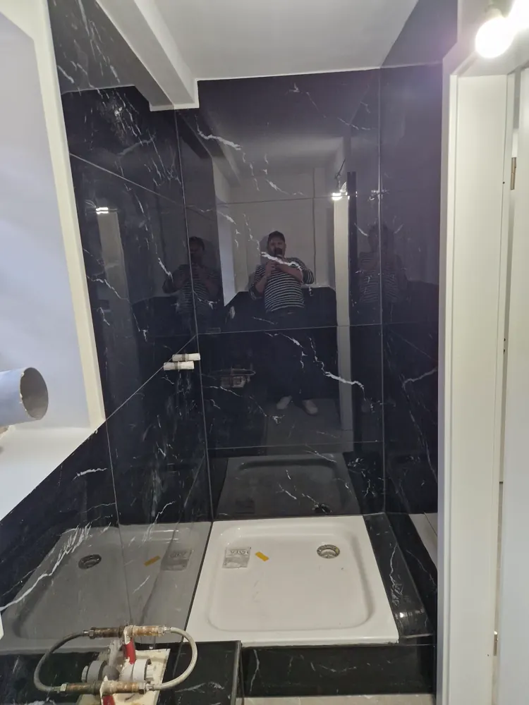 Duschbereich in schwarzem Marmor mit Glastrennwand und zwei Duschwannen