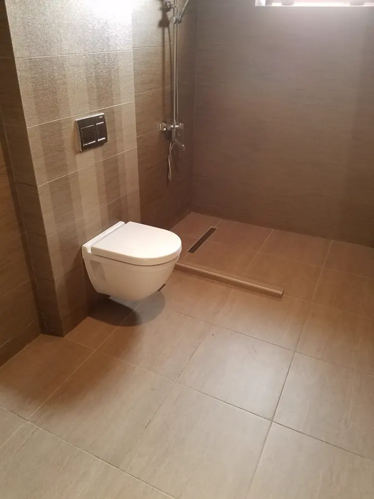 Bad in Beigetönen mit Wand-WC und bodengleicher Dusche mit Wandablauf
