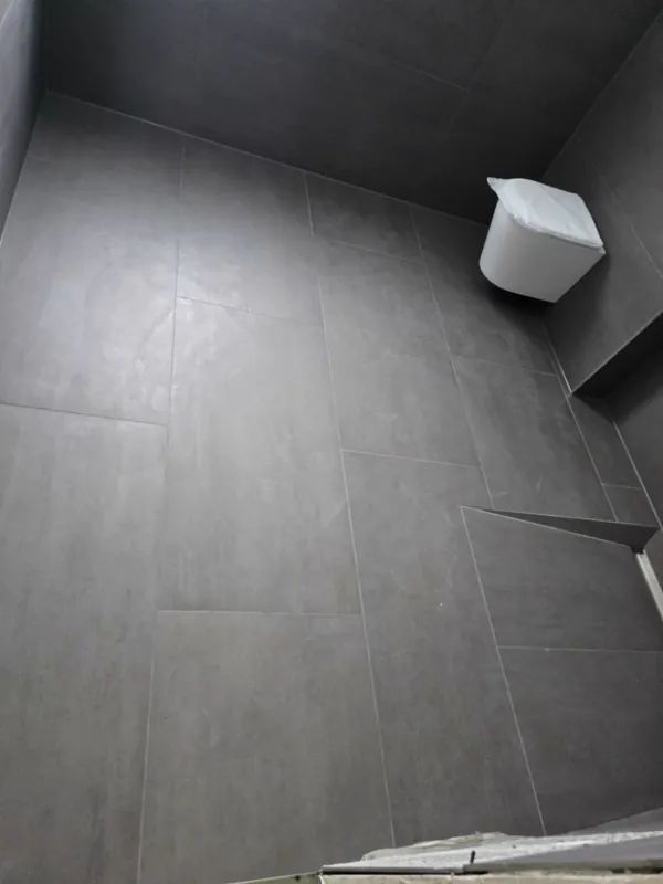 Großformatige graue Fliesen an Wand und Boden mit schmalen Fugen und Wand-WC