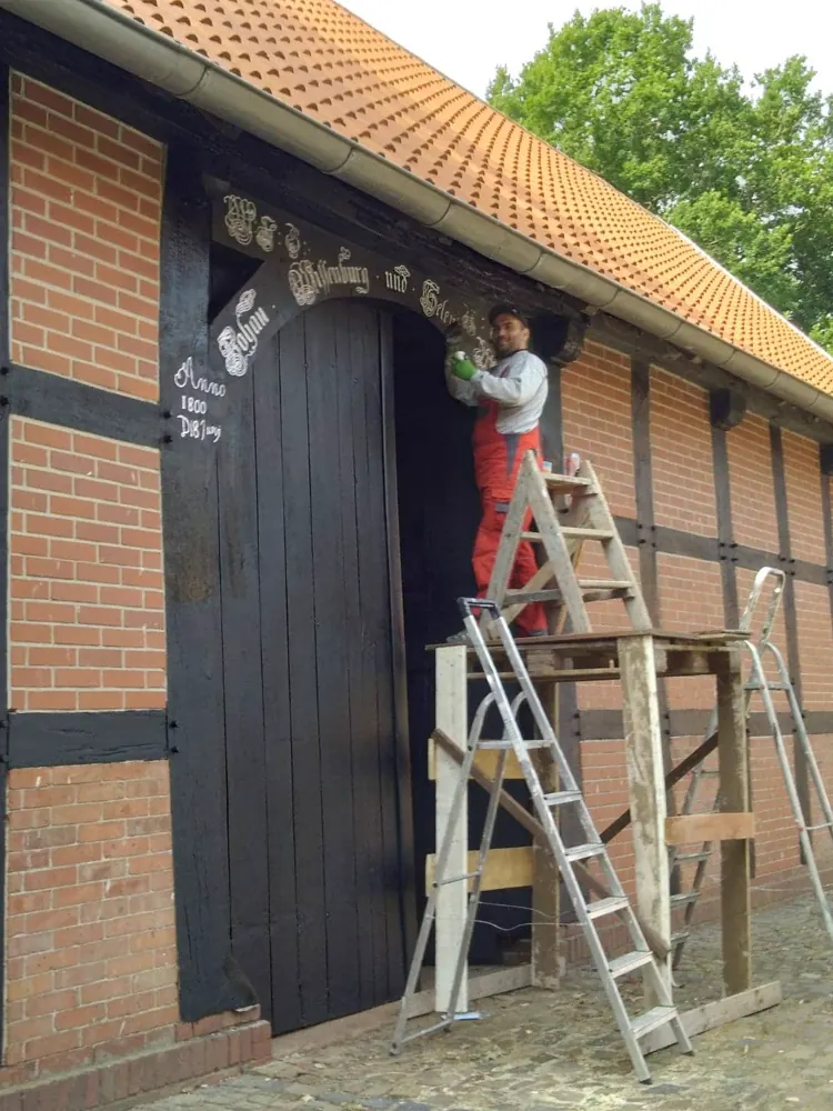 Arbeiten am Fachwerk einer historischen Fassade von der Leiter aus
