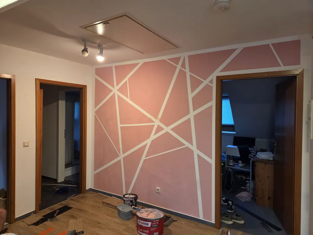 Wand mit geometrischem Linienmuster in Altrosa und Weiß in einem Wohnraum