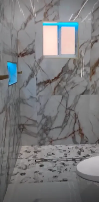 Bodengleiche Dusche in Marmoroptik mit Kieselboden und Duschrinne