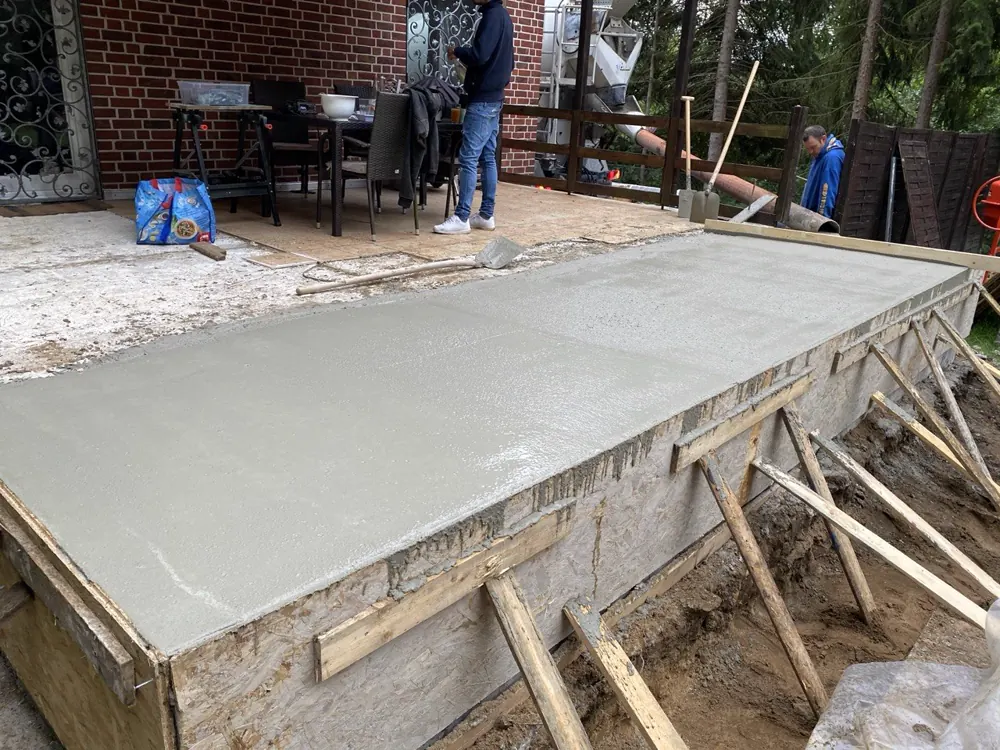 Frisch betonierte und abgezogene Bodenplatte der Terrasse in der Holzschalung
