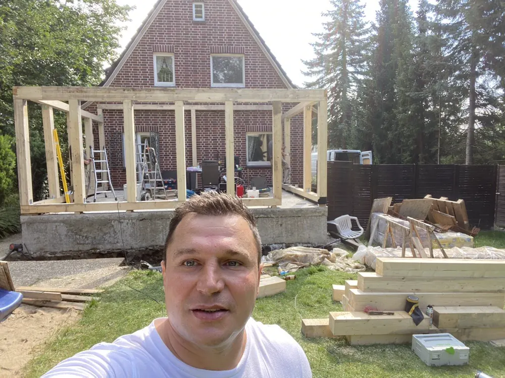Aufgestellter Holzrahmen der Terrassenüberdachung vor dem Backsteinhaus