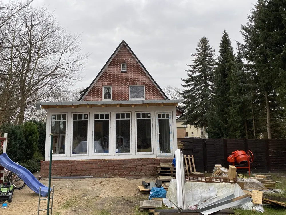 Fertig verglaste Veranda am Backsteinhaus mit umlaufenden Fensterelementen