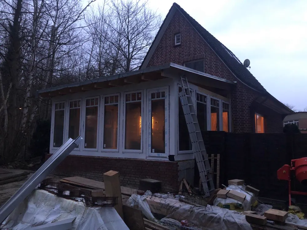 Die verglaste Veranda am Abend, von innen beleuchtet
